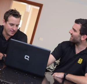 Two men talking in front of laptop