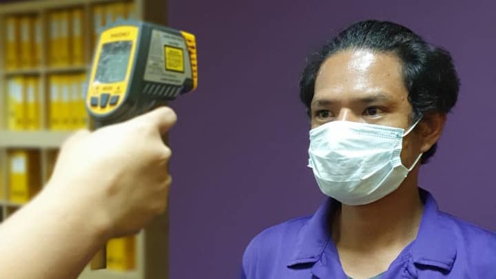 Man wearing mask getting temperature taken with thermometer gun
