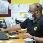 We will fix it employee wearing mask and headset using computer