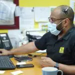 We will fix it employee wearing mask and headset using computer