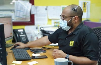 We will fix it employee wearing mask and headset using computer