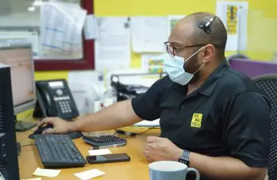 We will fix it employee wearing mask and headset using computer