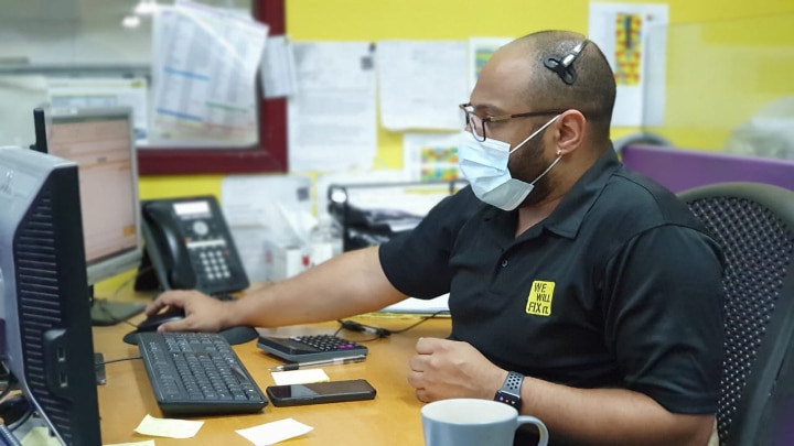 We will fix it employee wearing mask and headset using computer