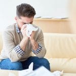Man sneezing on tissue