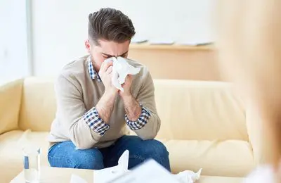 Man sneezing on tissue