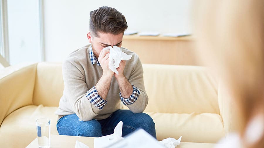 Man sneezing on tissue