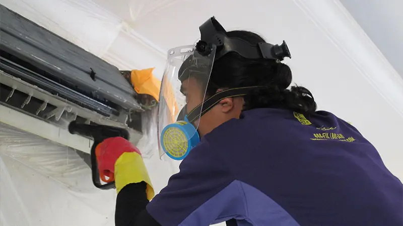 We will fix it employee with mask cleaning air conditioner