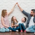 Family of four raising hands over children