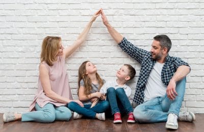 Family of four raising hands over children