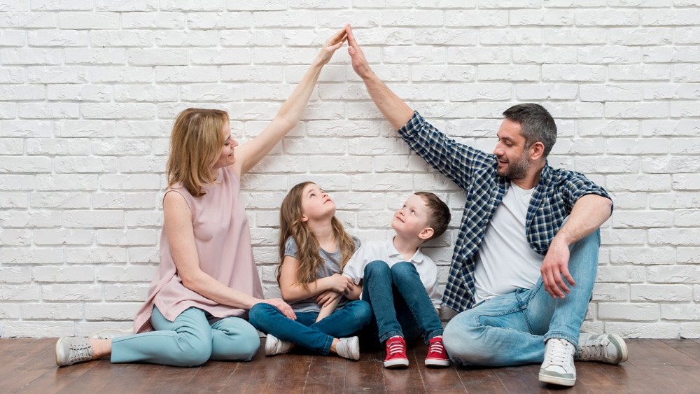 Family of four raising hands over children