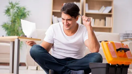 A confused man holding tools and instructions booklet
