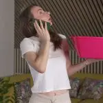 A woman on the phone looking up holding a bucket