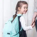School girl smiling and holding hands with woman