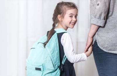 School girl smiling and holding hands with woman
