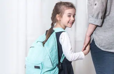 School girl smiling and holding hands with woman