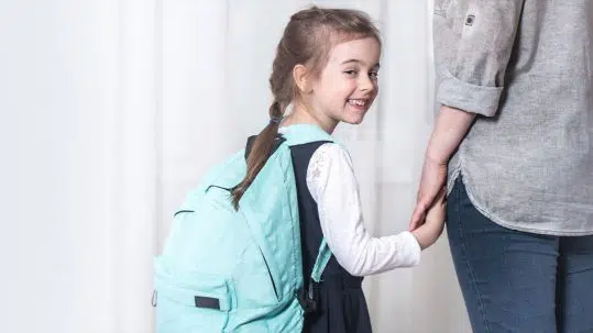 School girl smiling and holding hands with woman