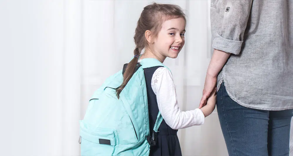 School girl smiling and holding hands with woman