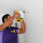 We will fix it employee drilling on dry wall with drill machine