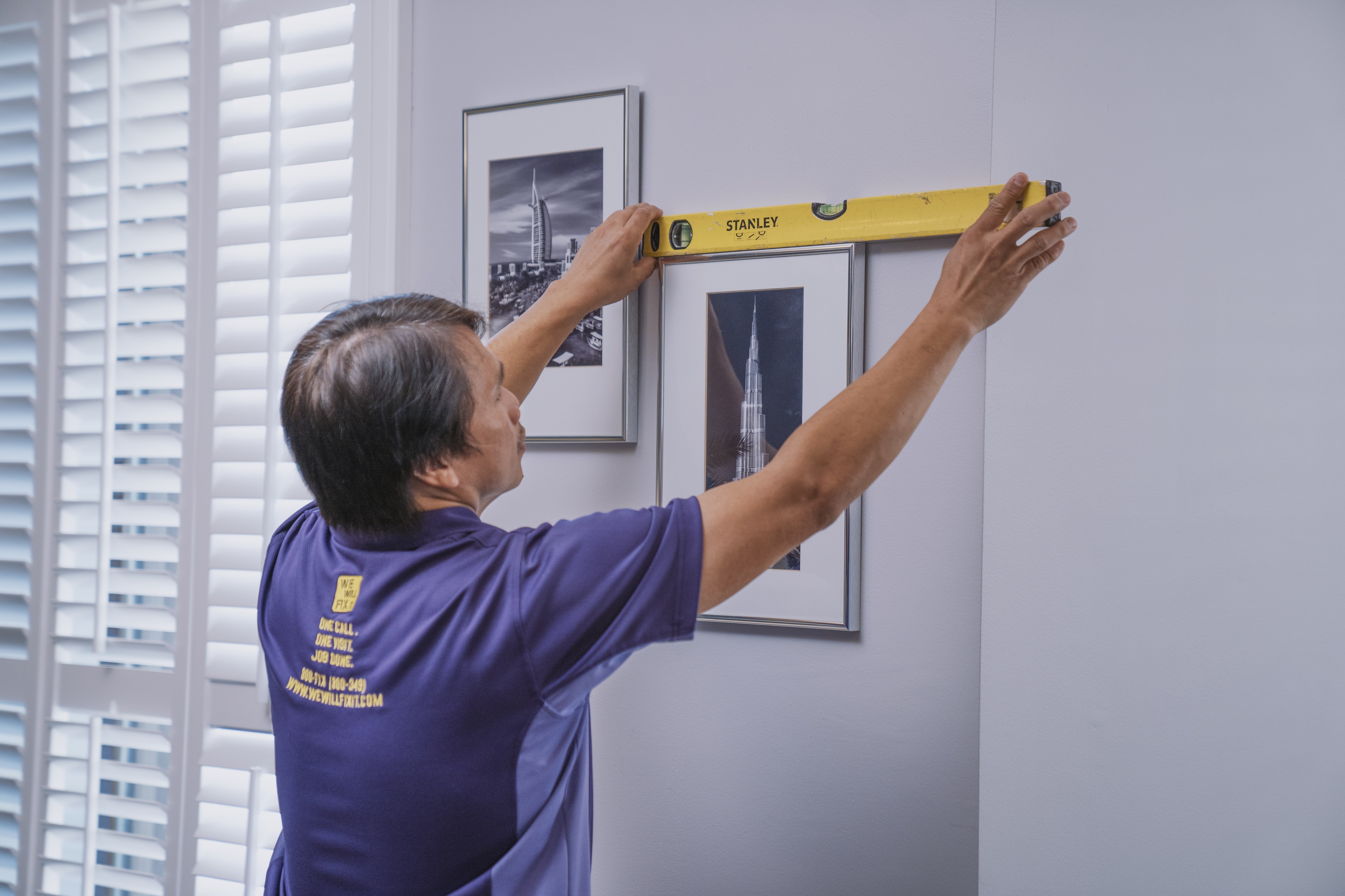 Handyman hanging frames on the wall