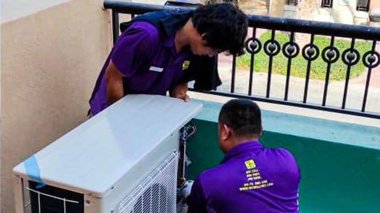 Two technicians performing AC maintenance